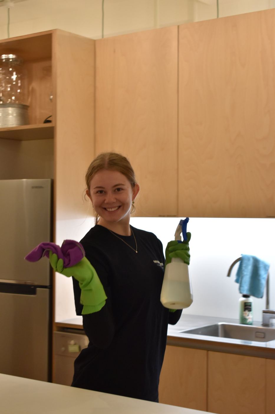 Smiling Scrubbies cleaner in an office kitchen with spray bottle and cloth