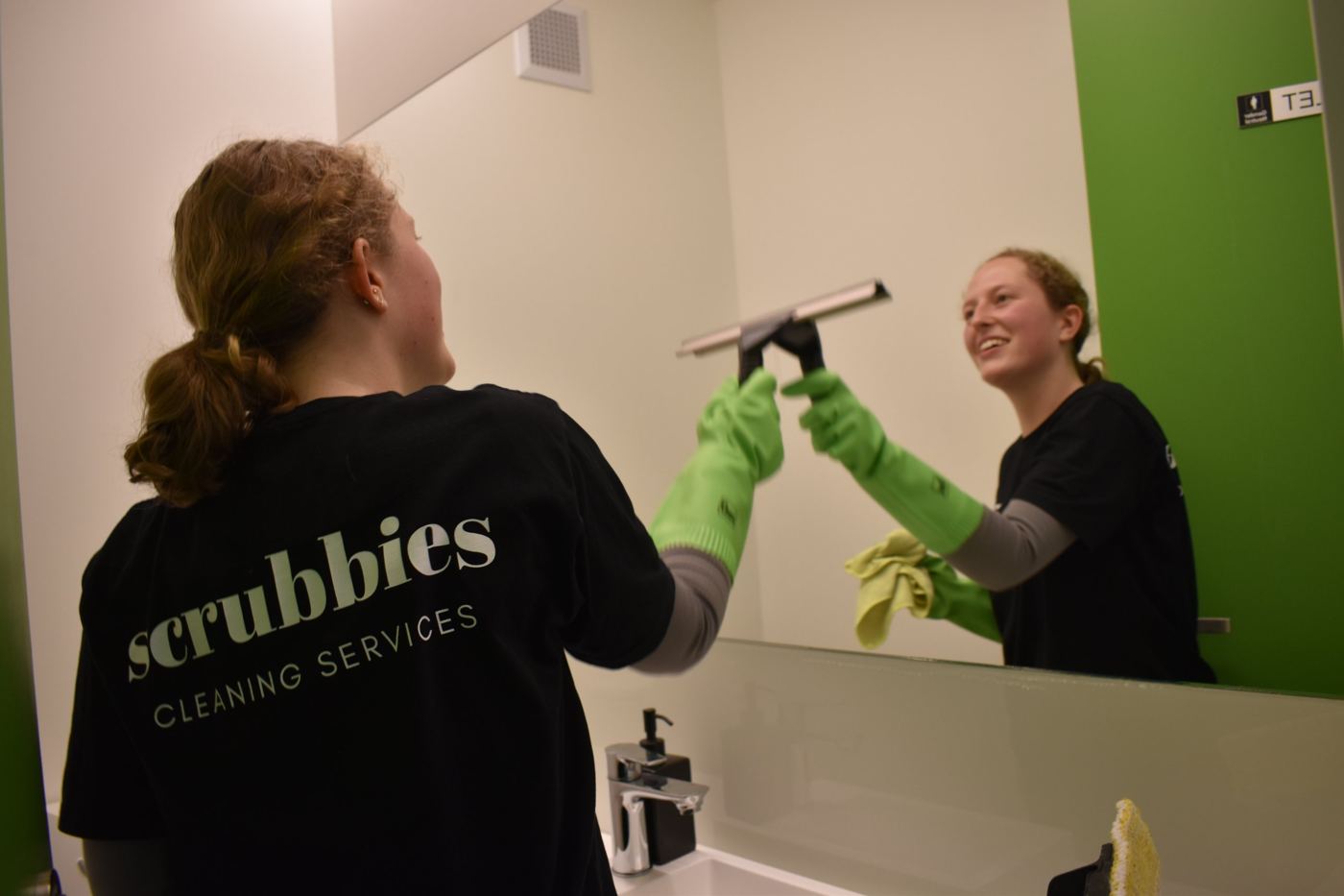 Scrubbies cleaner squeegeeing a washroom mirror