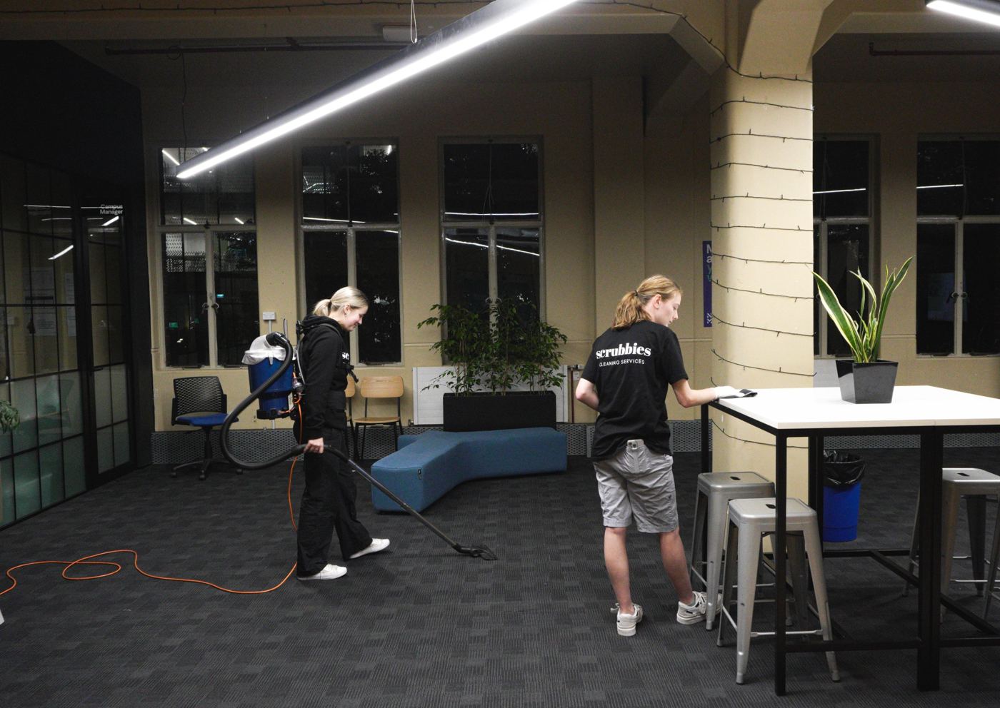 Scrubbies cleaners vacuuming and wiping tables in an open-plan office